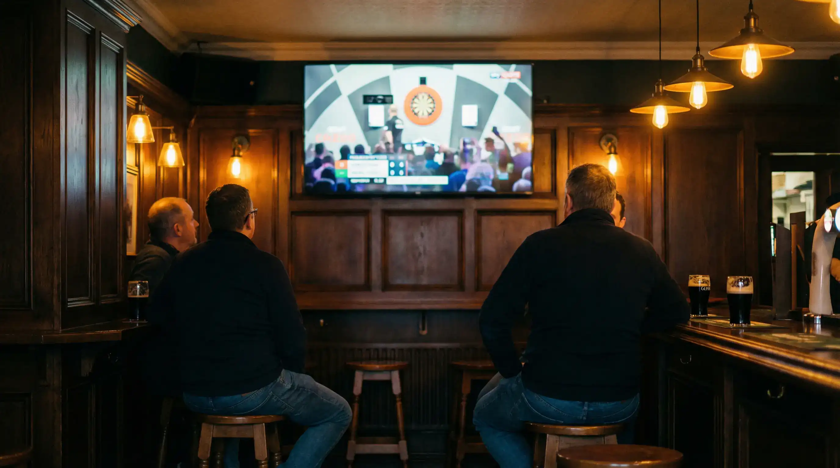Irish sports pub with patrons watching live darts on screen